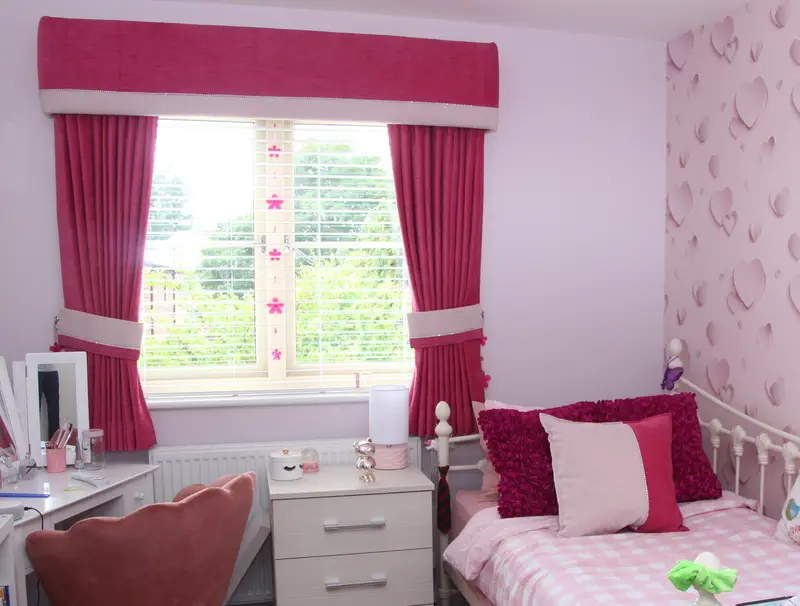 Coordinated pink curtains, pelmet and cushions in a bedroom by Heather Horrocks Leigh